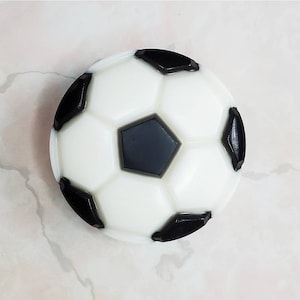 May include: A white and black soccer ball shaped soap. The soap is round and has a classic soccer ball design.