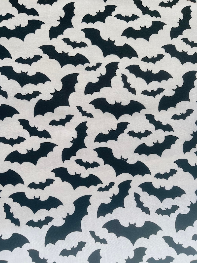K&ouml;nnte beinhalten: Ein wei&szlig;er Stoff mit einem sich wiederholenden Muster aus schwarzen Fledermaus-Silhouetten.