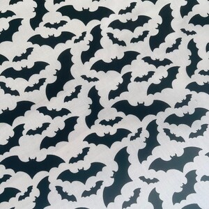 K&ouml;nnte beinhalten: Schwarz-wei&szlig;es Stoffmuster mit einem sich wiederholenden Muster von Flederm&auml;usen. Die Flederm&auml;use sind wei&szlig; und der Hintergrund ist schwarz.