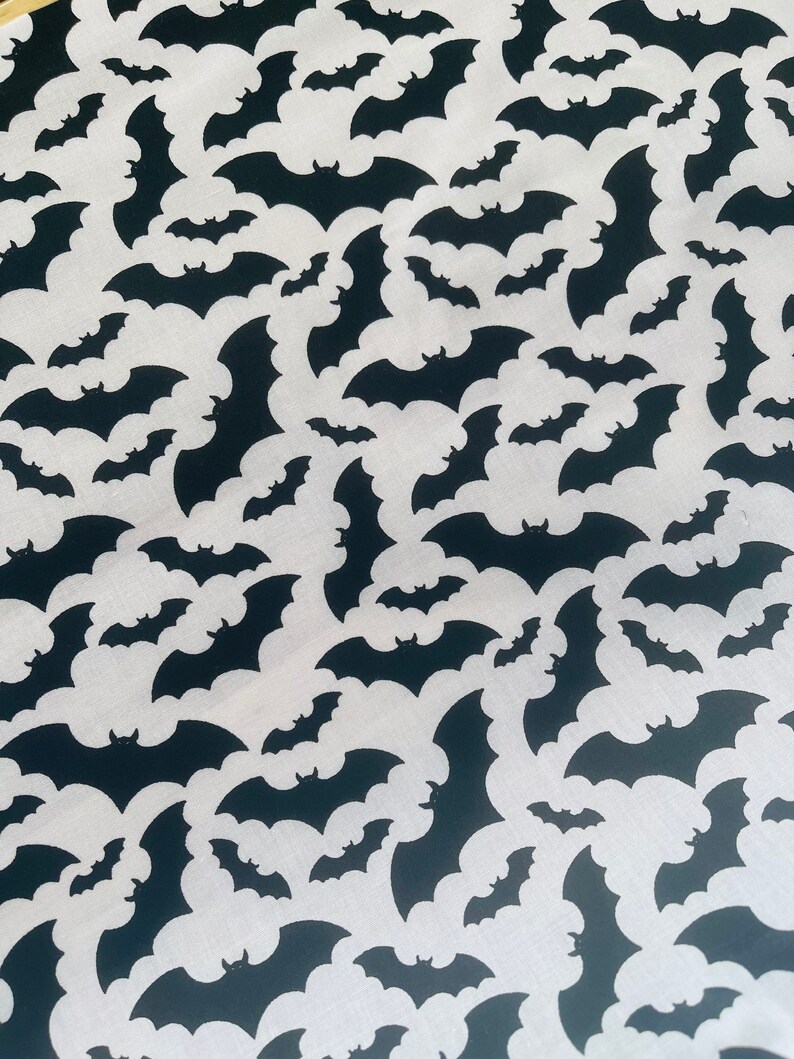K&ouml;nnte beinhalten: Schwarz-wei&szlig;es Stoffmuster mit einem sich wiederholenden Muster von Flederm&auml;usen. Die Flederm&auml;use sind wei&szlig; und der Hintergrund ist schwarz.