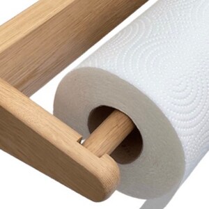 Puede incluir: Un soporte de papel de cocina de madera con un rollo de papel de cocina blanco. El soporte est&aacute; montado en la pared y tiene una clavija de madera para que el papel de cocina pueda girar alrededor.