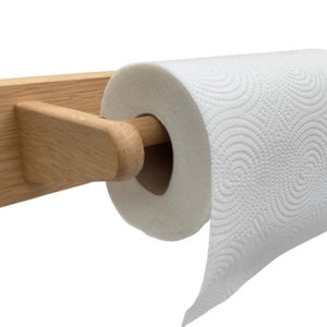 Puede incluir: Un soporte de papel de cocina de madera con un acabado natural. El soporte est&aacute; montado en la pared y tiene una varilla de metal para sujetar el rollo de papel de cocina.