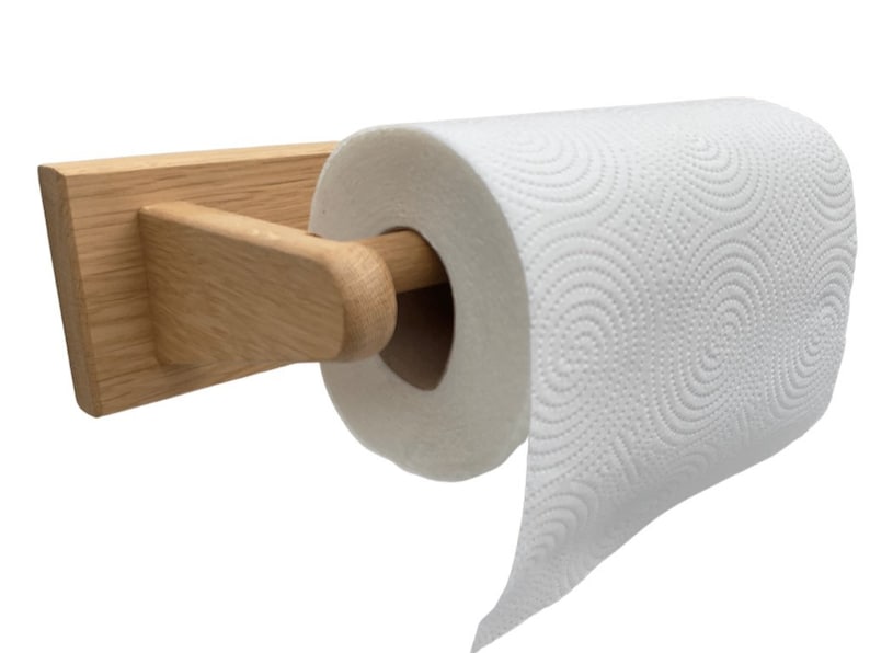 Puede incluir: Un soporte de papel de cocina de madera con un acabado natural. El soporte est&aacute; montado en la pared y tiene una varilla de metal para sujetar el rollo de papel de cocina.