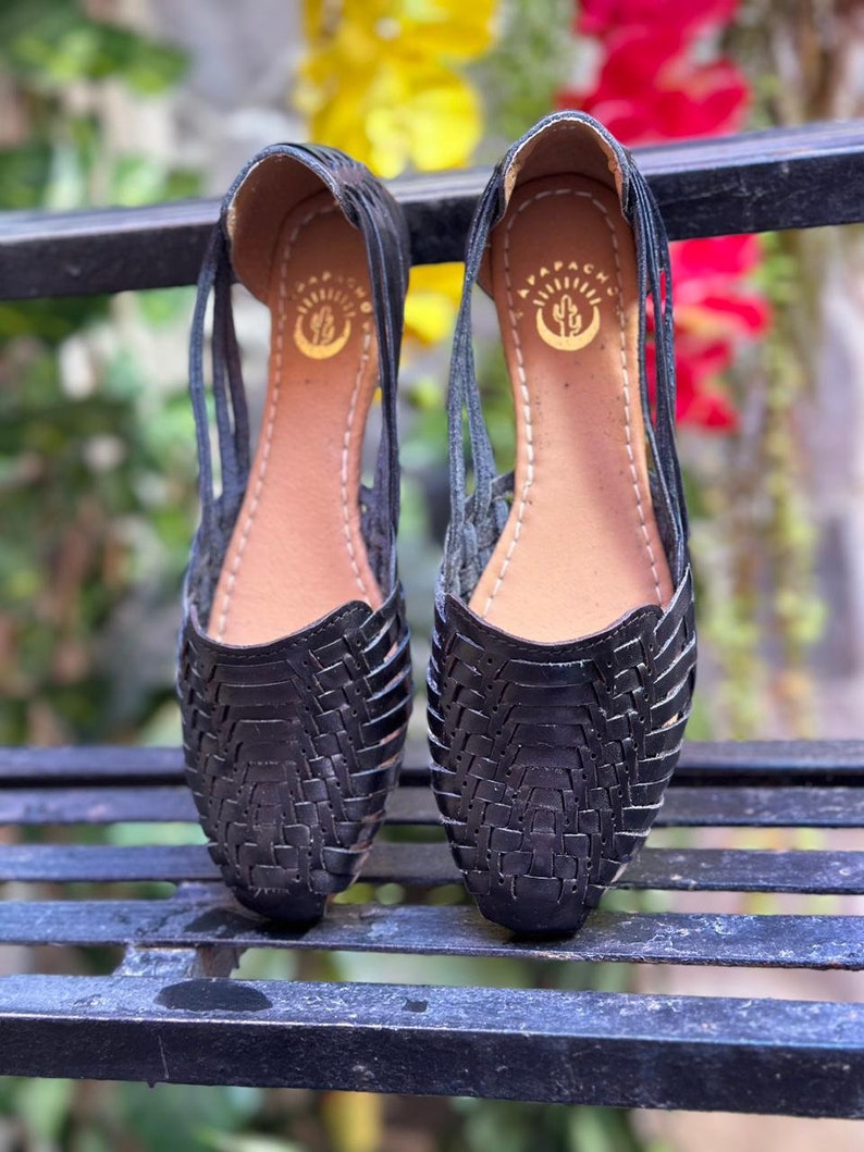 May include: A pair of black leather sandals with a woven design. The sandals have a small cactus logo on the insole.