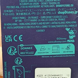 May include: A product tag with text in multiple languages, including English, French, and Chinese. The tag includes recycling information, a barcode, and the Disney logo. The tag indicates the product is made in China.