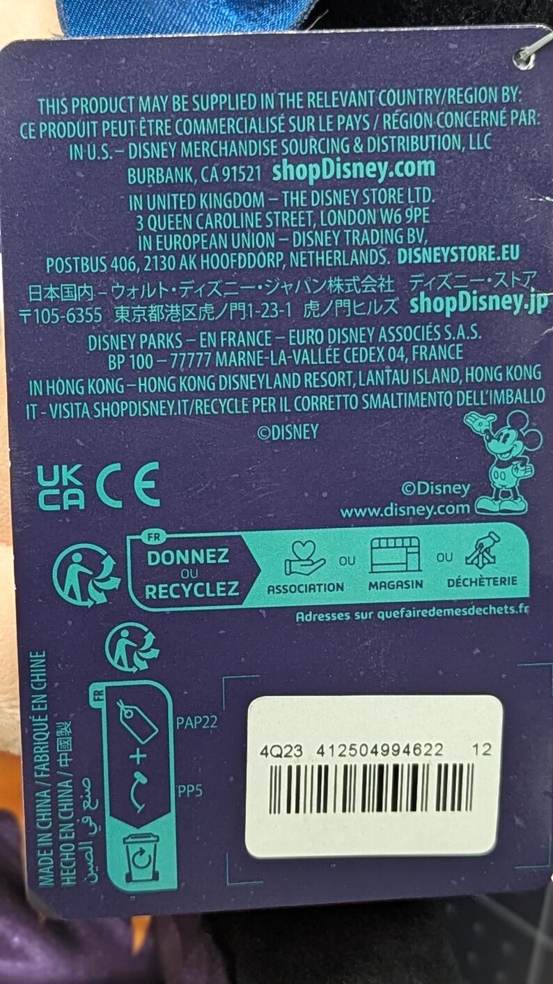 May include: A product tag with text in multiple languages, including English, French, and Chinese. The tag includes recycling information, a barcode, and the Disney logo. The tag indicates the product is made in China.