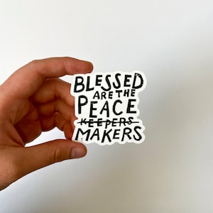 May include: White sticker with black text that reads "Blessed are the peace makers" with the word "keepers" crossed out.