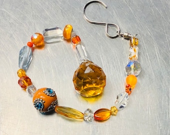 May include: A beaded suncatcher with a large amber crystal, orange and clear glass beads, and a silver hook.