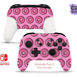 Könnte beinhalten: Rosafarbener Nintendo Switch Pro Controller mit Donut-Muster. Der Controller hat einen rosa Hintergrund mit weißen Donuts mit rosa Zuckerguss und bunten Streuseln.