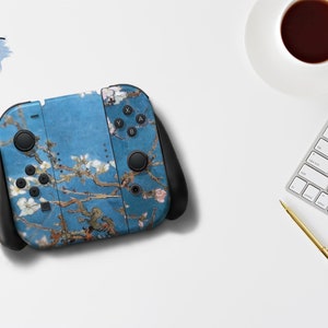 Puede incluir: Un mando Nintendo Switch Joy-Con azul y blanco con un diseño floral. El mando tiene botones negros y una empuñadura negra.
