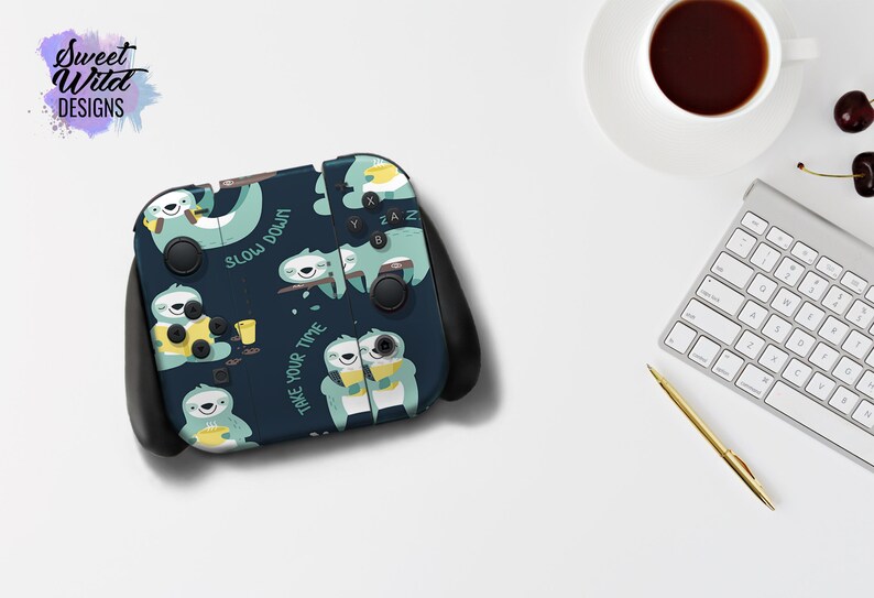 Pu&ograve; includere: Una skin per console Nintendo Switch blu scuro con un motivo ripetitivo di bradipi che tengono tazze e il testo "Slow Down" e "Take Your Time".