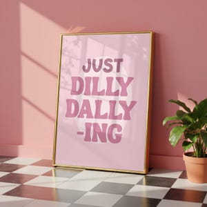 May include: A framed pink poster with the words "JUST DILLY DALLY -ING" in a retro font. The poster is leaning against a pink wall, with a potted plant in the corner. The floor is a black and white checkered pattern.
