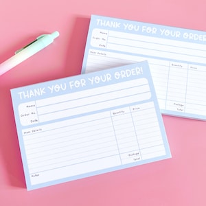 May include: Two light blue order forms with the text "THANK YOU FOR YOUR ORDER" in white. The forms have sections for name, order number, date, item details, quantity, price, postage, and total. A pen with a gradient of colors is in the background.