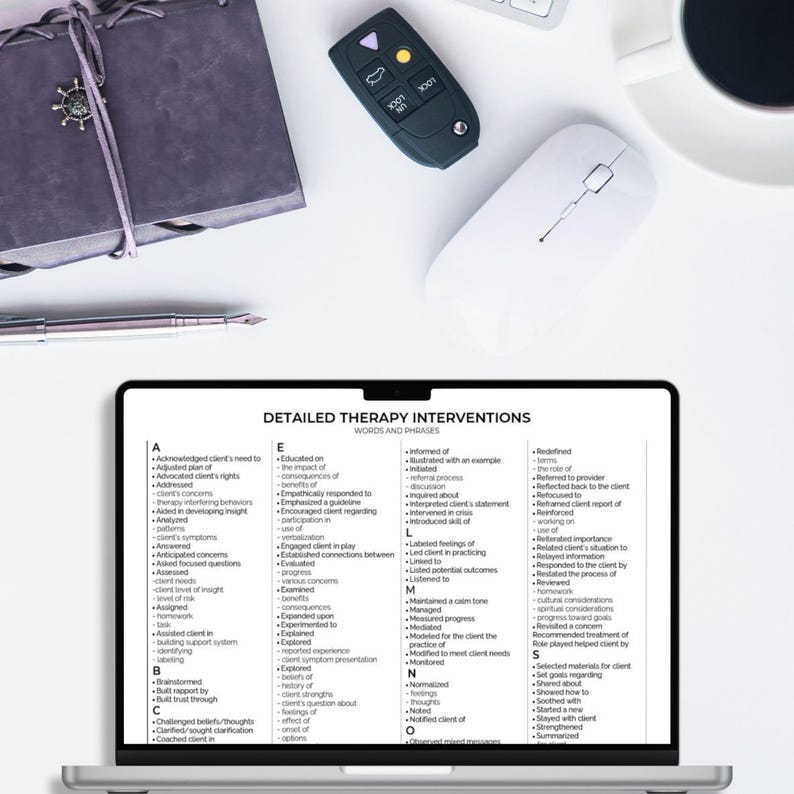 May include: A laptop screen displaying a document titled Detailed Therapy Interventions with an alphabetical list of clinical words and phrases. Nearby are a dark gray notebook with a silver charm, a black car key fob, a white computer mouse, and a pen.