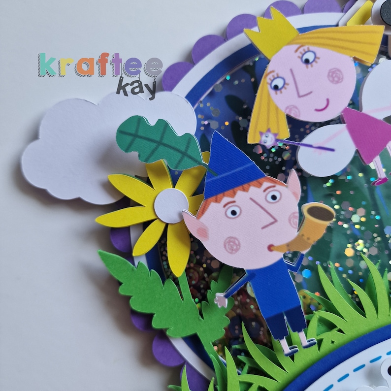 May include: A papercraft scene featuring a fairy and a gnome. The fairy is wearing a pink dress and a crown, and she is holding a wand. The gnome is wearing a blue hat and a blue shirt, and he is playing a horn. The scene is set in a forest with green leaves and yellow flowers.