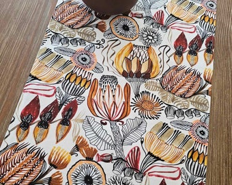 May include: A white table runner with a floral pattern featuring orange, red, and black flowers. The flowers are stylized and have a modern design. The runner is perfect for adding a touch of color and style to any table.