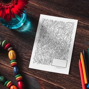 Pu&ograve; includere: Una pagina da colorare in bianco e nero con un disegno floreale. La pagina &egrave; su un tavolo di legno con un fiore rosso, una collana di perline colorate e matite colorate.