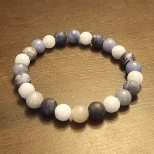 May include: A blue, white, and gray beaded bracelet with a variety of stone beads.