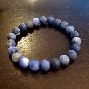 Könnte beinhalten: Ein blaues Edelstein-Armband mit runden Perlen. Das Armband besteht aus natürlichen Steinen und hat ein schlichtes Design.