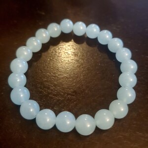 May include: A light blue beaded bracelet made of round, smooth stones.