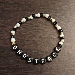 May include: Black and white beaded bracelet with the word "GHOSTFACE" spelled out in black beads.