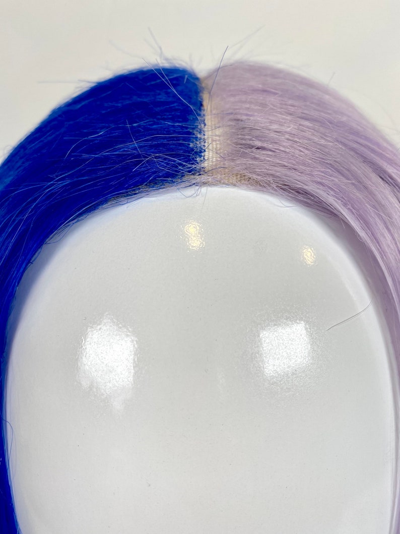 May include: A half blue and half lavender wig on a white mannequin head.