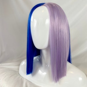 May include: A half blue and half lavender wig with straight, blunt cut ends. The wig is on a white mannequin head.