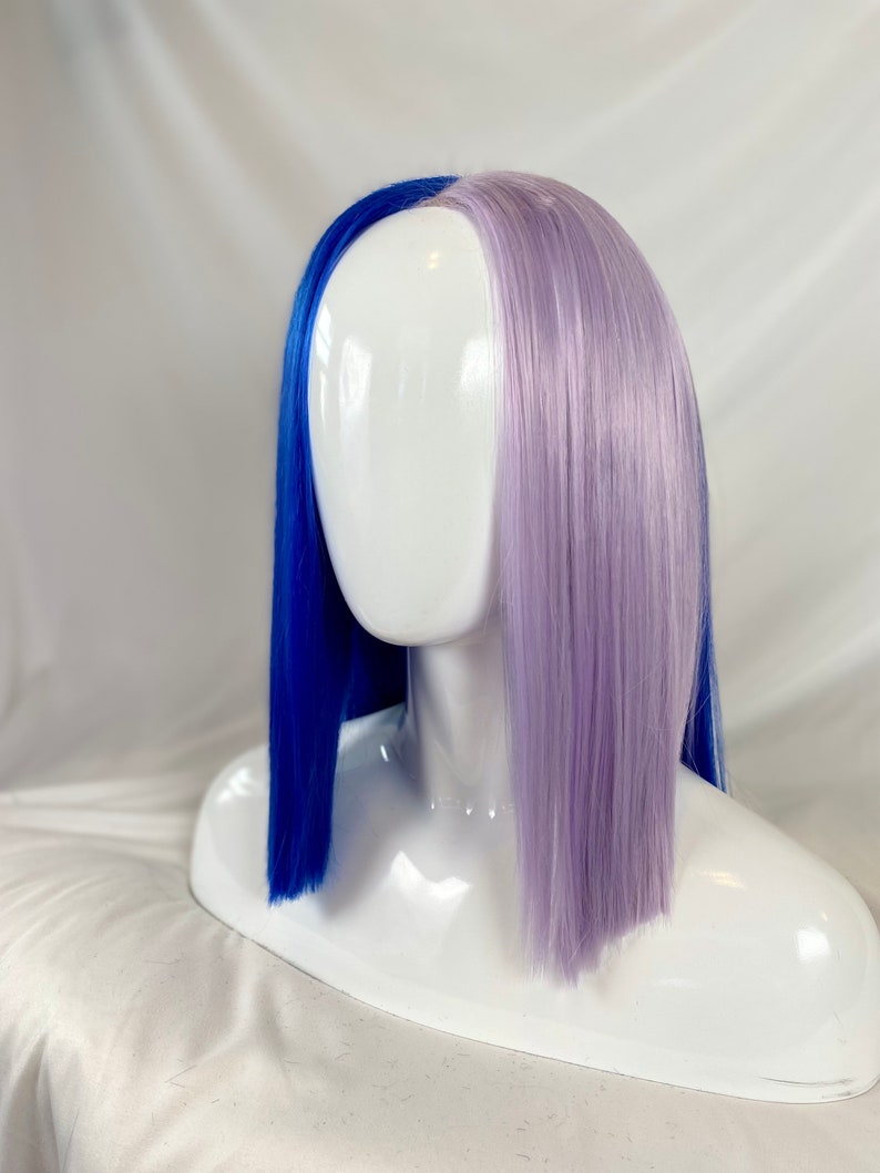 May include: A half blue and half lavender wig with straight, blunt cut ends. The wig is on a white mannequin head.