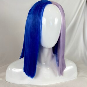 May include: A blue and lavender wig with straight, shoulder-length hair. The wig is split down the middle, with one side blue and the other side lavender.