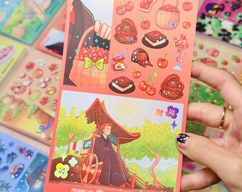 May include: A sheet of stickers featuring illustrations of cherries, desserts, and a person in a traditional Japanese setting. The stickers are in shades of red, pink, and brown. The sheet is held by a hand with a decorated nail.