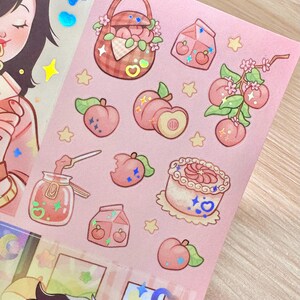 May include: A sheet of pink stickers featuring peach-themed illustrations. Designs include peaches, a picnic basket, a cake, and a jar of jam. The stickers have a cute, cartoonish style with holographic accents and star shapes.