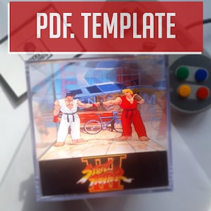 Op de afbeelding: Een doorzichtige acrylbox met een scène uit het spel Street Fighter III met twee vechtende personages. De box heeft een zwarte basis met het logo van het spel. De bovenkant van de afbeelding heeft de tekst "PDF. TEMPLATE" in wit op een rode achtergrond.