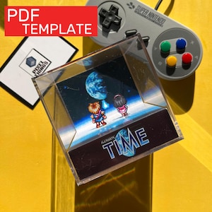 Puede incluir: Un cubo de exhibición de acrílico transparente con una escena pixelada del juego "Illusion of Time", que muestra dos personajes y un planeta. El cubo está sobre una superficie amarilla, con un mando de Super Nintendo y una tarjeta que dice "PDF TEMPLATE".