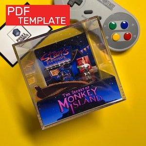 May include: A clear acrylic display case featuring a miniature diorama of "The Secret of Monkey Island." The diorama includes figures and a scene from the game, with the text "Stan's previously owned vessels."