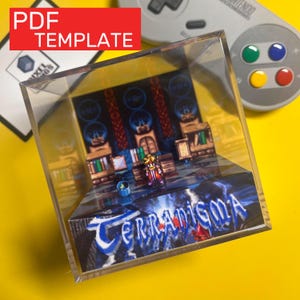 Puede incluir: Un cubo de exhibición de acrílico transparente con un diorama en miniatura de una escena de videojuego. El diorama incluye una figura de personaje, edificios y la palabra "Terranigma". La esquina superior izquierda tiene un rectángulo rojo con las palabras "PDF TEMPLATE".