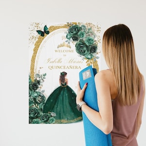 May include: A green and gold Quincea&ntilde;era welcome sign with a floral design and a butterfly. The sign says "Welcome to Isabella Maria's Quincea&ntilde;era".