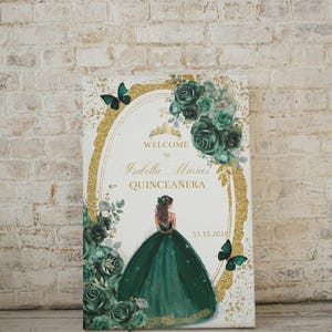 May include: A welcome sign for a Quincea&ntilde;era, featuring a gold glitter background with a green floral design and a silhouette of a girl in a green dress. The text reads "Welcome to Isabella Maria's Quincea&ntilde;era 11.15.2022".