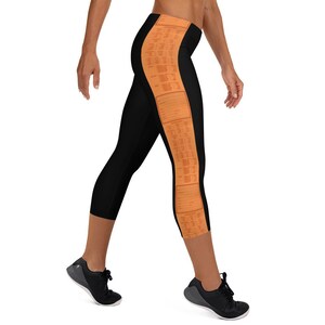 May include: Black capri leggings with a vertical orange and white patterned stripe on the right leg.