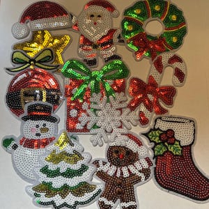 May include: A collection of Christmas-themed sequin patches. Includes Santa Claus, a wreath, a candy cane, a snowman, a Christmas tree, a gingerbread man, a stocking, a star, a gift, and a snowflake. The patches are in red, green, gold, and white.