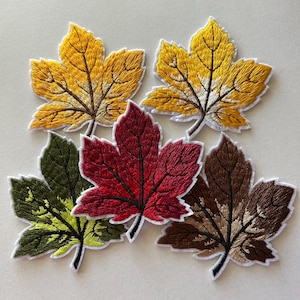 May include: Embroidered leaf patches in various autumn colors: yellow, red, brown, and green. Each patch features detailed stitching to mimic leaf veins, with a white border. These patches are ideal for adding a seasonal touch to clothing or accessories.