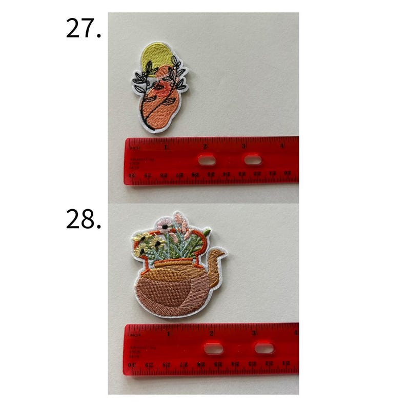 May include: Two embroidered patches. The top patch features an abstract design with orange, yellow, and black accents. The bottom patch depicts a brown teapot filled with colorful flowers. Both patches are on a white background.