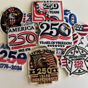 May include: A collection of embroidered fabric patches commemorating the United States 250th anniversary. The patches feature red, white, and blue designs, bald eagle illustrations, American flags, and text including 250 Years, 1776-2026, and Independence.