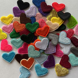 May include: A collection of embroidered heart patches in various colors, including red, yellow, green, blue, and purple. The patches are made of fabric and have a stitched border. These heart-shaped patches are ideal for crafts and DIY projects.