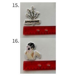 May include: Two embroidered patches. The top patch features a sprig of white flowers with green leaves and the text "Love yourself" on a tan banner. The bottom patch depicts a figure with a black head covering and tan skin.