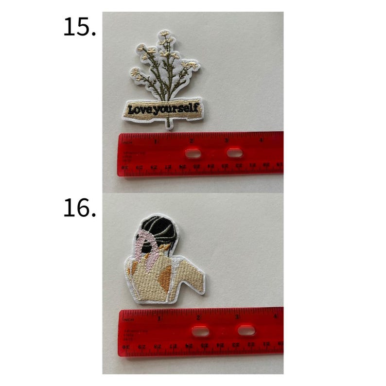 May include: Two embroidered patches. The top patch features a sprig of white flowers with green leaves and the text "Love yourself" on a tan banner. The bottom patch depicts a figure with a black head covering and tan skin.