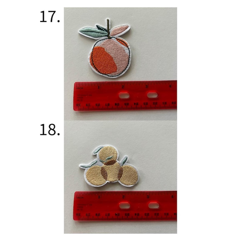May include: Embroidered patches featuring fruit designs. One patch depicts a peach with orange, pink, and green details, while the other shows three golden-yellow fruits with green leaves. A red ruler is placed below each patch.