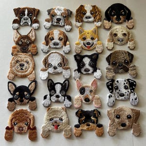 May include: A collection of embroidered dog patches in various breeds and colors. The patches feature detailed stitching, showcasing different dog breeds with their unique characteristics. The dogs are in a playful pose, with their paws extended.