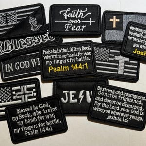 May include: A collection of black embroidered patches with religious and patriotic themes. The patches feature phrases like "Faith over Fear," "Blessed," and Bible verses. Some patches include American flag designs and crosses.
