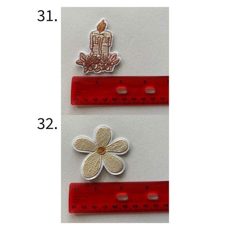 May include: Two embroidered patches: a candle and a flower. The candle patch is brown with a gold flame and floral accents. The flower patch is beige with a gold center and white border. A red ruler is next to each patch.