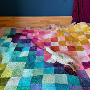 Colorful handmade quilt made of ombre confetti fabrics and embroidery by Tula Pink